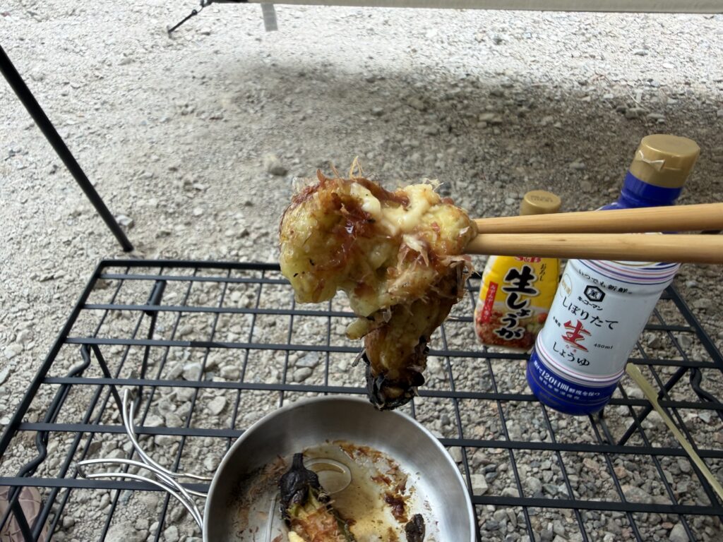 カツオ節と生姜醤油をかけた、とろとろの焼きナスを箸で持ち上げた様子