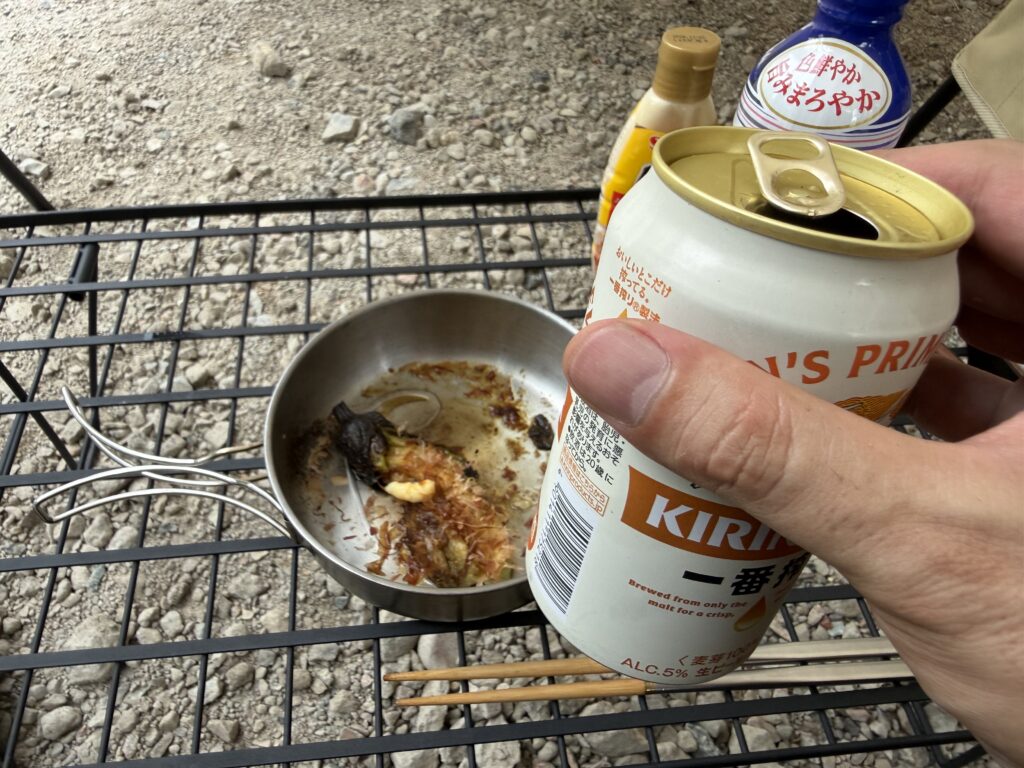 直火で焼いたナスをつまみに、ソロエリアで缶ビールを飲む様子