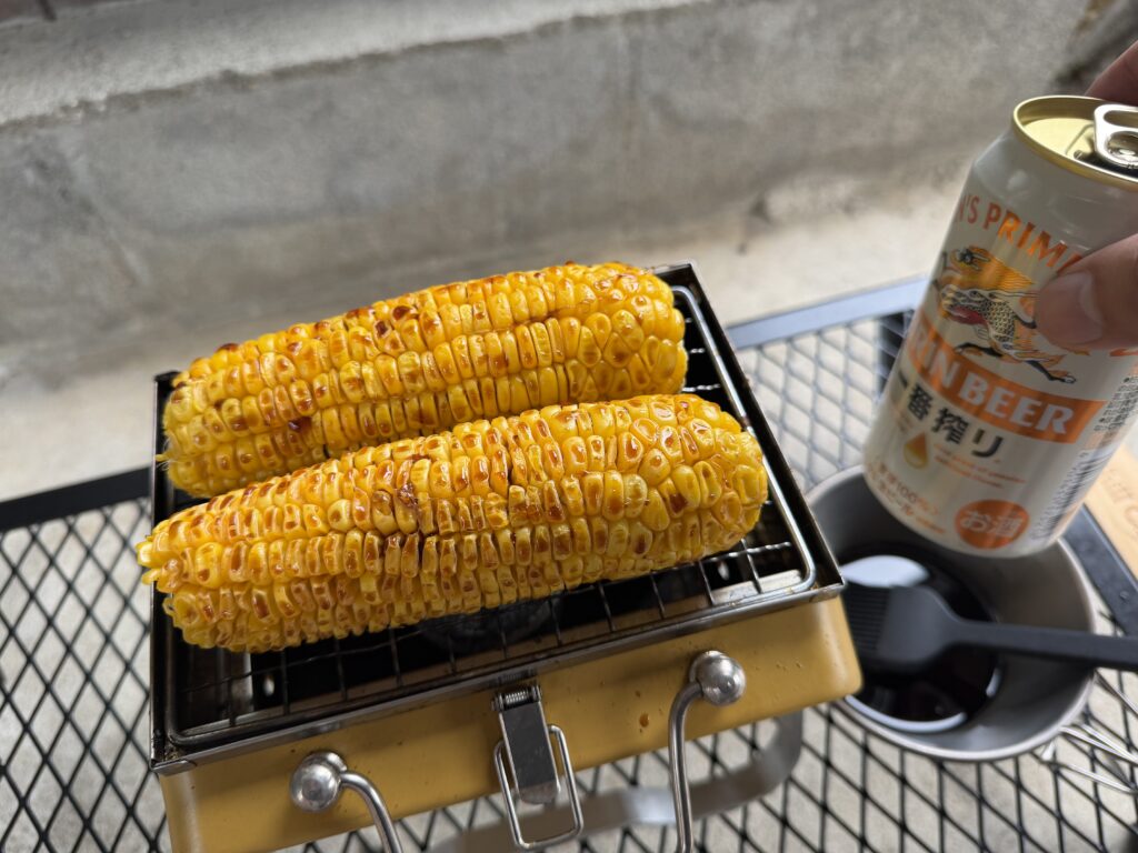 砂糖醤油を塗って炭火で焼いているとうもろこしとビール