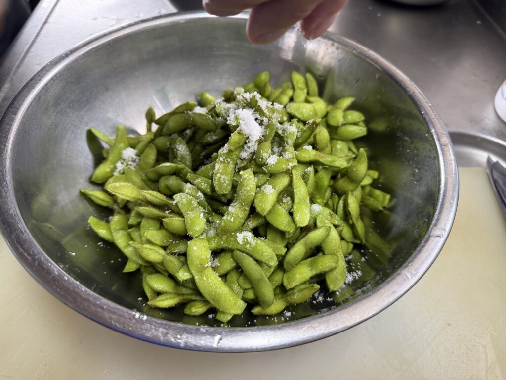 洗った枝豆へ塩を振りかける様子