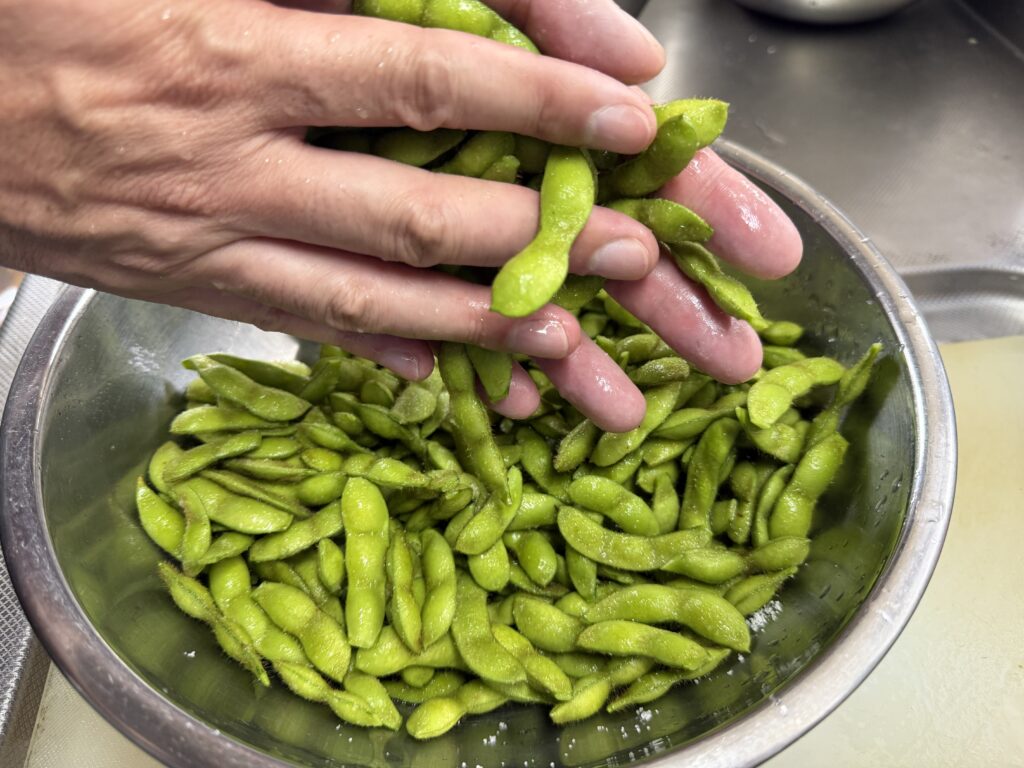 収穫した枝豆を両手で塩もみする様子