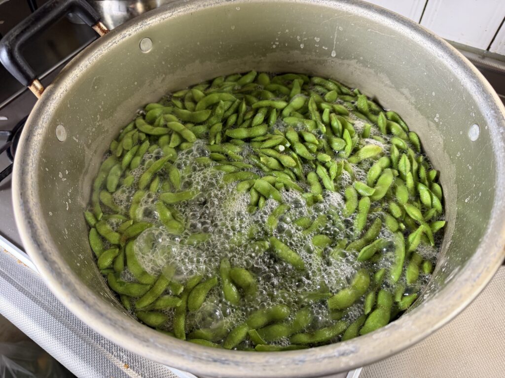 水3リットルと塩を入れた大きな鍋で枝豆を茹でる様子
