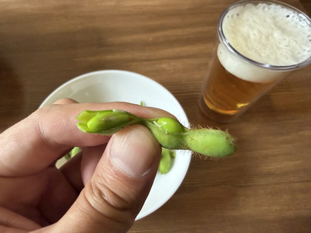 塩茹でした枝豆の莢を開いて見える緑色の豆