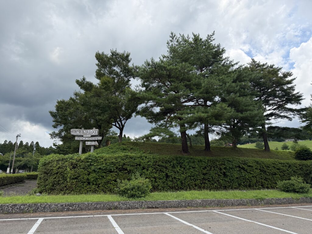 夏空と木々に囲まれた閑乗寺公園キャンプ場の入口看板