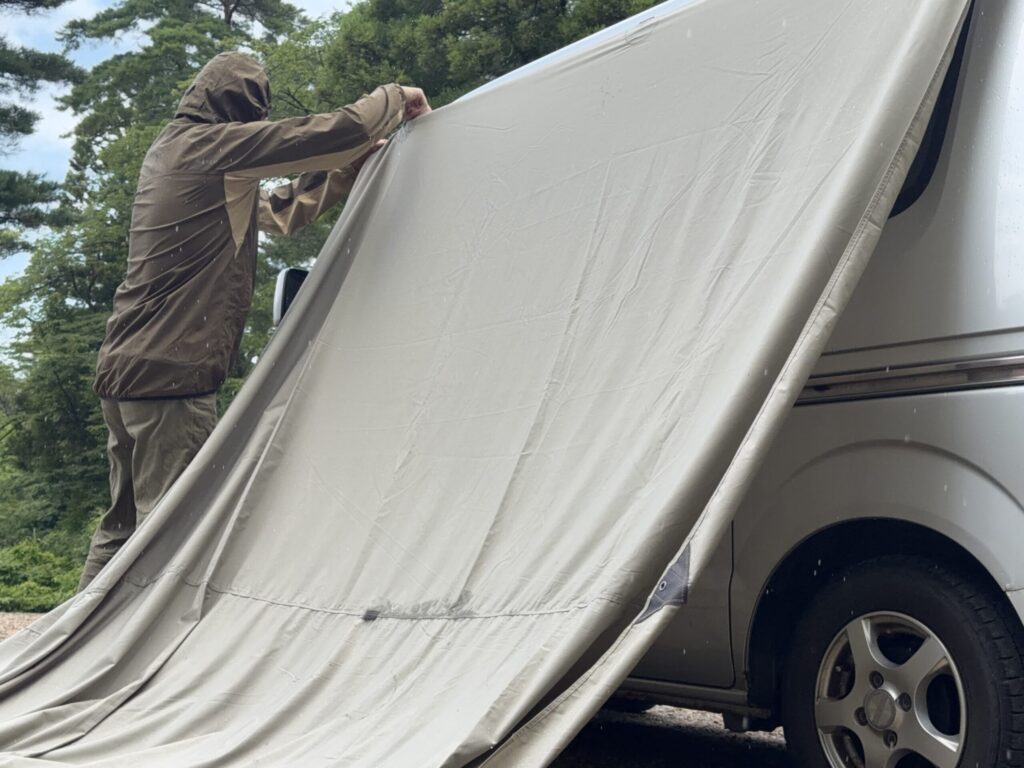 レインウェアを着てエブリイの横にTatonka Tarp 4 TCを設営する様子