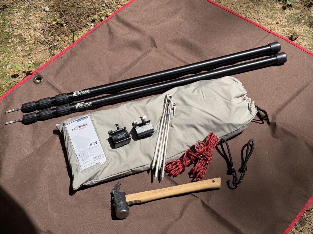 タープの上に並べたTATONKA Tarp 4 TCとポールやペグなどの設営道具