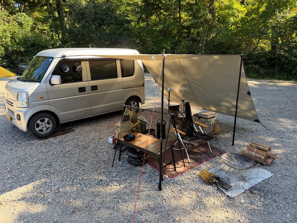 エブリイの横にタープを張りチェアやテーブル、焚き火台を配置したソロキャンプサイト