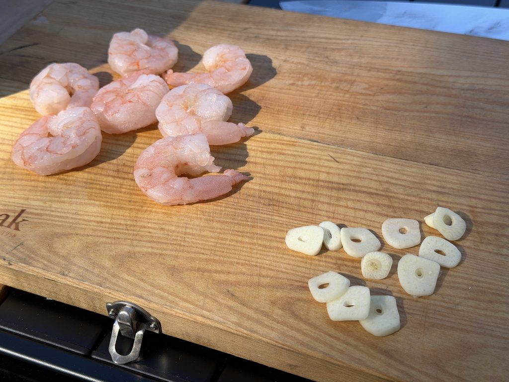 まな板に並べたむきエビとスライスしたニンニク