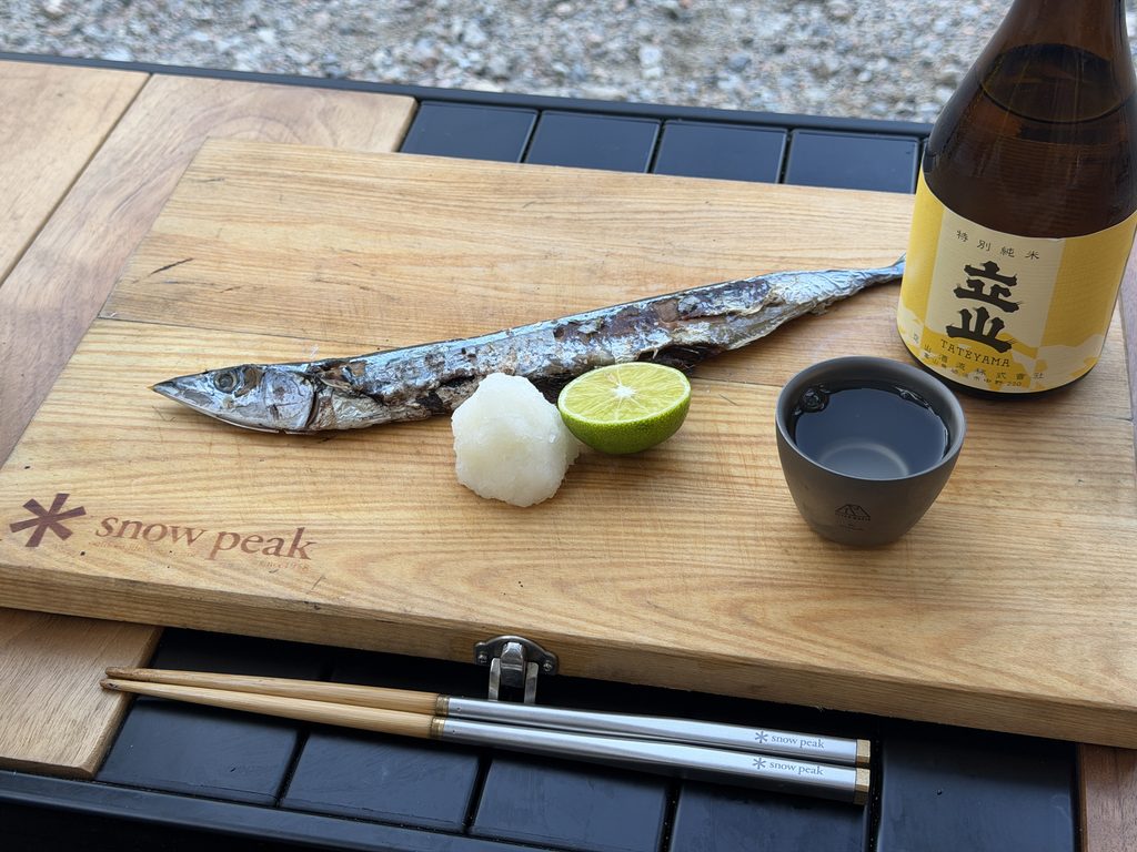 サンマの炭火焼きと立山特別純米の瓶、チタンのぐい呑み