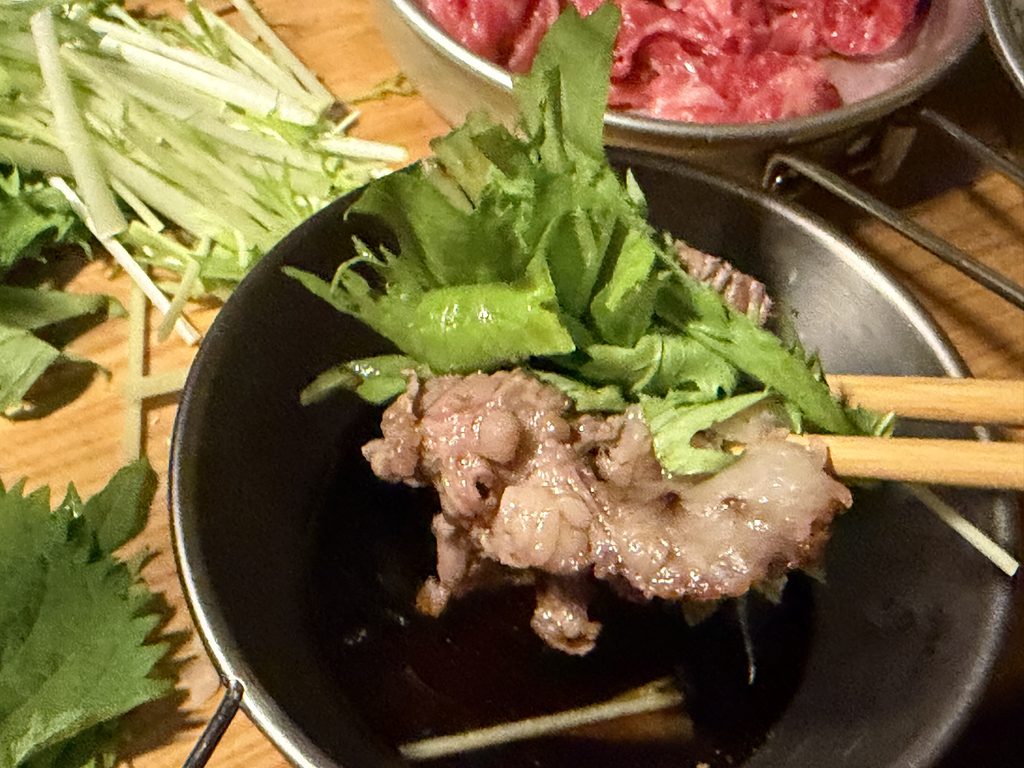 焼いた博多和牛に水菜を合わせ、箸で持ち上げた様子