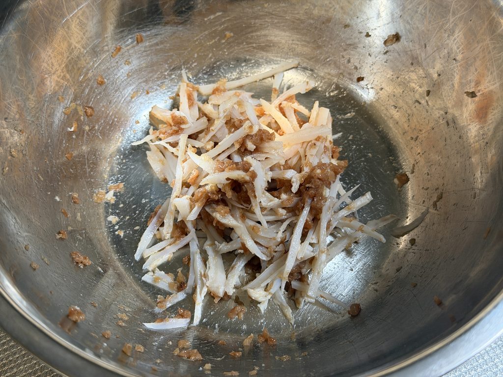 細切りのヤゲン軟骨に、たたいたはちみつ梅の梅肉を加えて和えた様子